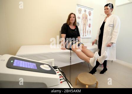 Heiligendamm, Germania. 23 aprile 2020. Susanne Herpold (l), curata paziente Covid-19, e Jördis Frommhold, vice-medico capo, si comunicano tra loro nella mediana Klinik durante una elettrostimolazione neuromuscolare per stimolare la crescita muscolare e muscolare. Susanne Herpold era molto gravemente malata, era in coma artificiale per 13 giorni. È una delle prime pazienti con una malattia grave sopravvissuta di Covid-19 che è arrivata alla Clinica mediana per il trattamento di follow-up. Credit: Bernd Wüstneck/dpa-Zentralbild/dpa/Alamy Live News Foto Stock