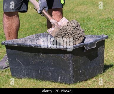 Malta di calcestruzzo mescolata in secchio nero con la spiade da lavoratore in giardino, primo piano Foto Stock