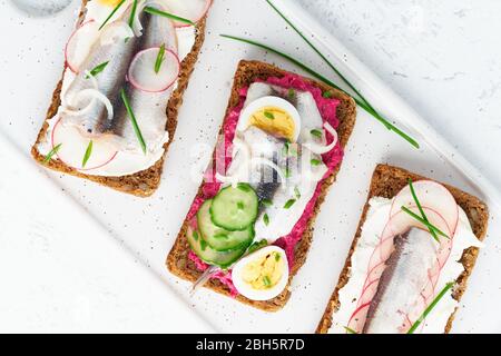Gustoso smorrebrod, due tradizionali panini danesi. Pane di segale nero con acciuga Foto Stock