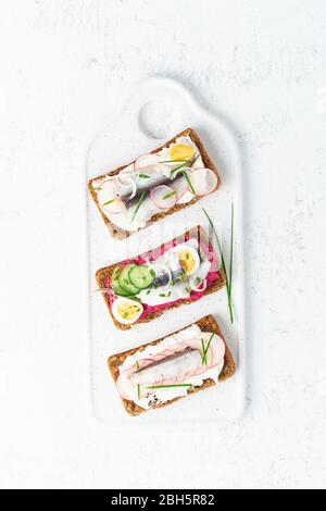 Gustoso smorrebrod, due tradizionali panini danesi. Pane di segale nero con acciuga Foto Stock