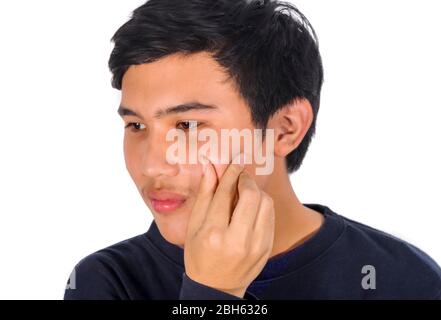 La foto di un uomo asiatico sta schiacciando acne sulla sua faccia. Foto Stock