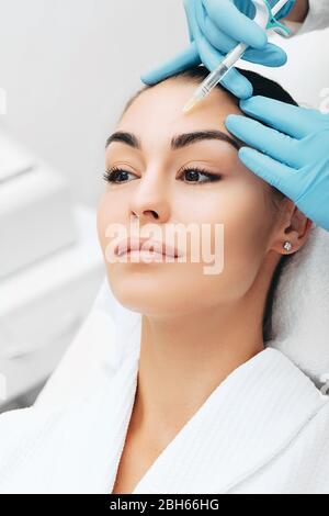 il medico inietta facendo l'iniezione per sollevare il viso di una donna bella per ottenere un effetto ringiovanente della pelle Foto Stock