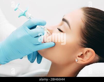 il medico inietta facendo l'iniezione per sollevare il viso di una donna bella per ottenere un effetto ringiovanente della pelle Foto Stock