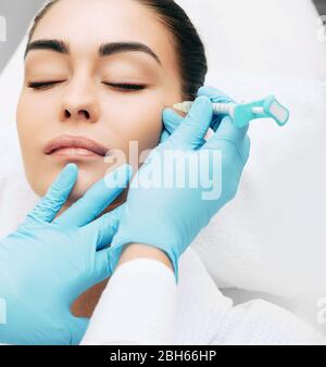 il medico inietta facendo l'iniezione per sollevare il viso di una donna bella per ottenere un effetto ringiovanente della pelle Foto Stock