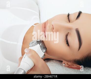 Il massaggio facciale a GPL porta il piacere alla donna, la pelle diventa più elastica. Primo piano faccia su sfondo bianco Foto Stock