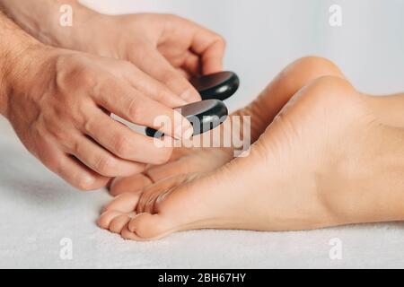 le feet femminili durante la procedura di massaggio con pietre calde, primo piano Foto Stock