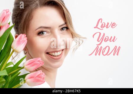 Love You mamma testo rosa e bella donna con tulipani rosa su sfondo bianco. Concetto di giorno della madre. Foto Stock