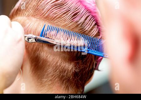 Vista posteriore delle mani del parrucchiere sono taglio donna capelli corti, primo piano. Foto Stock