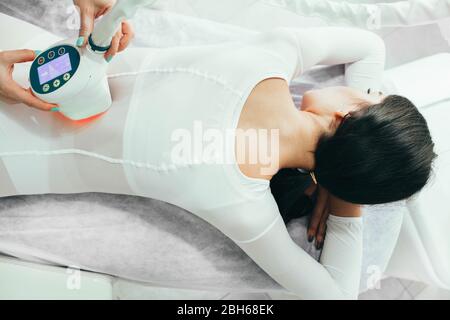 Rendendo sottile corpo con l'anti-cellulite massaggio GPL. donna vestito con una tuta speciale di ottenere una rimozione della cellulite massage Foto Stock