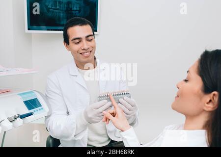 Dentista campionamento sfumature denti, tiene denti tavolozza sfumature vicino bocca femmina Foto Stock