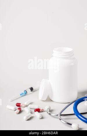 Concetto di trattamento medico. Varie pillole, stetoscopio e siringhe Foto Stock