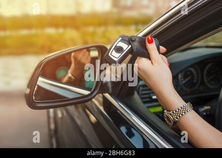 Mano femmina che tiene le chiavi dell'automobile dal finestrino dell'automobile Foto Stock