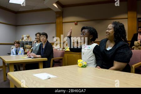 Austin, Texas, 20 novembre 2008: Celebrando la Giornata nazionale di adozione nel Texas centrale sono state 24 famiglie che hanno adottato i bambini in cerimonie festive alla corte Juvenile della contea di Travis. Alexus Giles (c) prende giuramento come la madre Penora Giles (r) la tiene. ©Bob Daemmrich Foto Stock