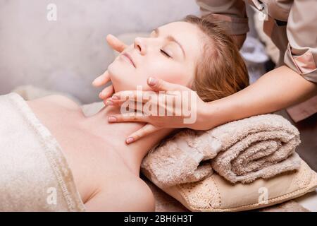 Donna caucasica con massaggio viso anti-invecchiamento. Spa Salon ringiovanente massaggio viso, primo piano Foto Stock