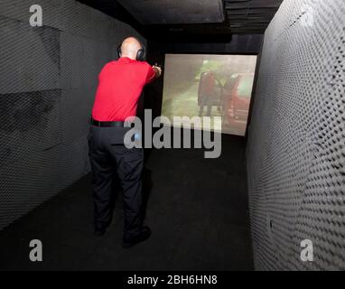 Austin, Texas USA, 30 giugno 2009: Un poliziotto di Austin dimostra una formazione antincendio in tempo reale all'interno di un laboratorio di formazione mobile acquistato per la città di Austin per formare i suoi poliziotti per le situazioni più impegnative. Il laboratorio utilizza una protezione in gomma spessa 12 cm per fermare i proiettili in tensione dopo essere stati sparati attraverso uno schermo video. ©Bob Daemmrich Foto Stock