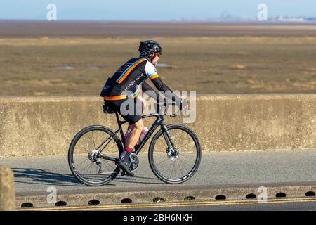 Southport, Merseyside. Meteo Regno Unito. 24 aprile 2020. Ancora un'altra luminosa giornata di primavera nel resort, in quanto i residenti locali si allenano alla luce. Donna a cavallo Signore Saracan bicicletta sul lungomare. Credit: MediaWorldImages/AlamyLiveNews Foto Stock