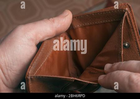 L'uomo mostra l'interno vuoto di un portafoglio in pelle marrone durante un periodo di crisi economica Foto Stock