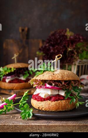 Panini, hamburger con pane integrale fatto in casa, aringhe, purè di barbabietola, cipolla rossa, prezzemolo e insalata di lattuga fresca Foto Stock