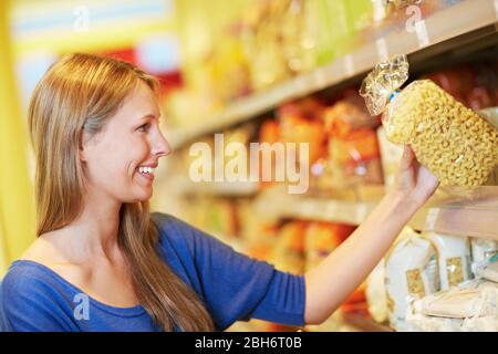 Una donna sorridente acquista delle tagliatelle di croissant in un supermercato Foto Stock