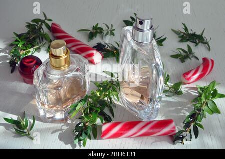 Bottiglie di profumo su una superficie di legno con caramello e rametti di mirto. Olio essenziale Foto Stock