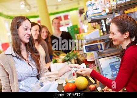 Una donna sorridente paga al check-out al supermercato Foto Stock