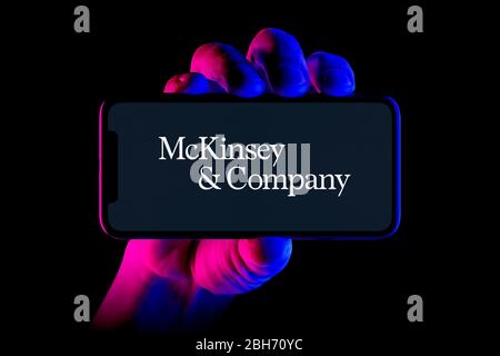 Uno smartphone con il logo McKinsey & Company è tenuto da una ripresa manuale su sfondo nero (solo per uso editoriale). Foto Stock