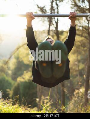 Giovane uomo bearded che fa tirare su nel parco con il tramonto bello sulla montagna Foto Stock