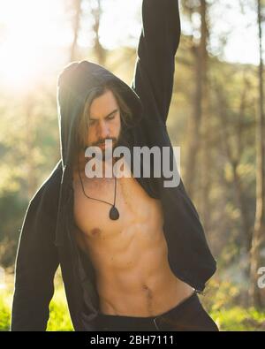 Giovane uomo bearded che fa tirare su nel parco con il tramonto bello sulla montagna Foto Stock