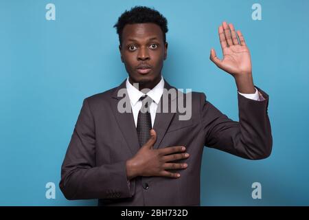 Africano americano maschio in tuta alzando palma e tenendo la mano sul petto Foto Stock