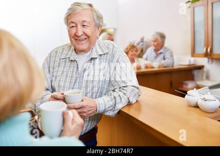 Uomo anziano soddisfatto che ha piccolo colloquio sopra il caffè nella casa di pensione Foto Stock