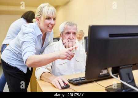 L'insegnante spiega a un senior come lavorare su un PC e su Internet in un corso di informatica Foto Stock