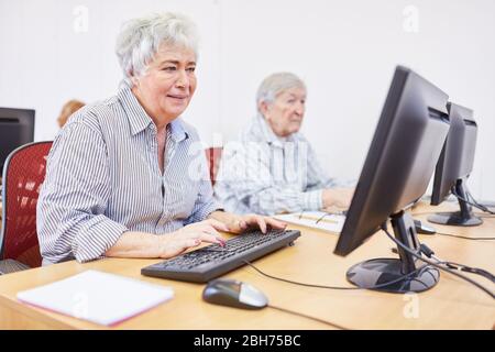 La donna anziana in una casa di riposo impara a utilizzare Internet su un PC in un corso di formazione al computer Foto Stock