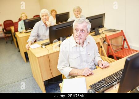 Gruppo di anziani in un corso di formazione su Internet e computer impara insieme sul PC Foto Stock