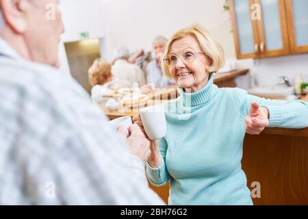 Gli anziani fanno un piccolo colloquio sopra una tazza di caffè nella lounge nella sede di ritiro Foto Stock