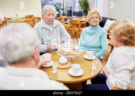 Gruppo di anziani nella pensione casa bere caffè e parlare nella sala comune Foto Stock