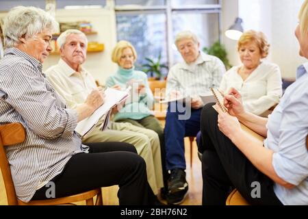 Gruppo di anziani con cuscinetto mentre dipingi e disegni in una terapia di pittura Foto Stock