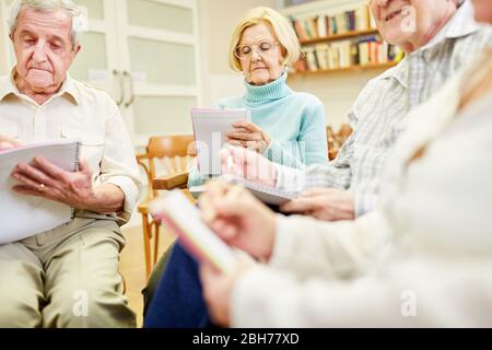 Gruppo senior con tampone di scrittura o di disegno in una terapia di scrittura Foto Stock