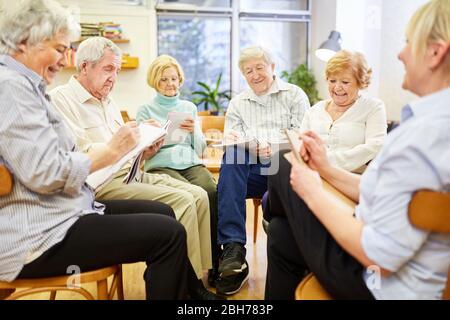Scrittura o disegno degli anziani con il cuscinetto di disegno in terapia di gruppo Foto Stock