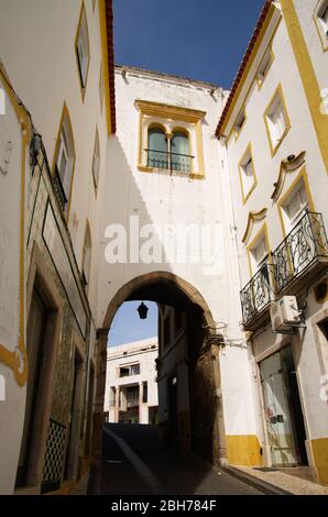 Casa ad arco bianca e gialla accanto alla piazza principale di Elvas, Piazza della Repubblica, su una stretta strada acciottolata. Questa è parte della seconda città Foto Stock