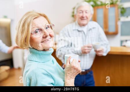 Anziani soddisfatti con una tazza di caffè che ha un piccolo colloquio nella sala nella casa di ritiro Foto Stock