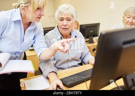 Il docente aiuta gli anziani sul PC con l'uso di Internet in un corso di computer del VHS Foto Stock