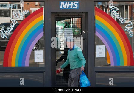 Anstey, Leicestershire, Regno Unito. 24 aprile 2020. Un uomo cammina davanti a un negozio con un tributo al NHS durante il blocco pandemico del coronavirus. Credit Darren Staples/Alamy Live News. Foto Stock