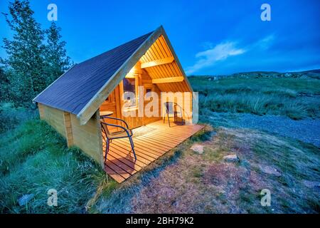 Bellissimo chalet isolato in montagna al tramonto. Frontale in legno con sedie Foto Stock
