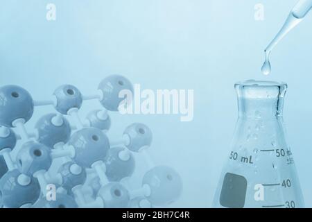 matraccio in vetro con goccia d'acqua in laboratorio di sciene medico blu con fondo per modello di chimica molecolare Foto Stock