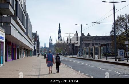 Centro di Edimburgo, Scozia, Regno Unito. 24 aprile. 2020. Quando arriviamo alla fine della quarta settimana del Coronavirus Lockdown c'era un centro eccezionalmente tranquillo con pochissimi veicoli o pedoni intorno ai monumenti storici della capitale scozzese che in tempi normali sarebbero stati circondati dai turisti in un soleggiato venerdì di metà mattina con una temperatura di 11 gradi. Nella foto: Princes Street con una coppia più anziana che cammina lungo il marciapiede quasi vuoto. Credit: Arch White/Alamy Live News Foto Stock