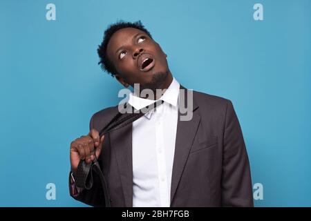 uomo stressato cercando di togliere la cravatta scomoda dopo una dura giornata di lavoro. Foto Stock