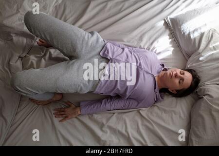 Giovane donna in ardha chakrasana yoga posa sul letto in la mattina Foto Stock