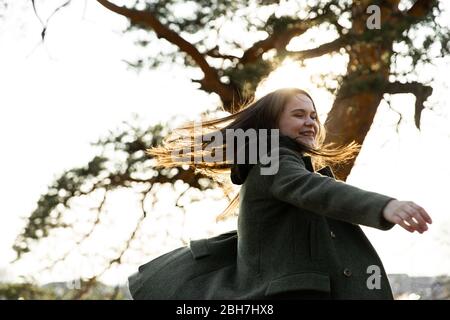 Bella donna nel parco. Ragazza che alza le braccia sorridendo felice. Giovane donna gioiosa sta girando nel parco primaverile Foto Stock