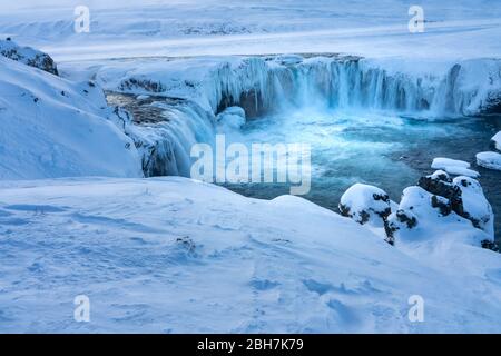 Il fiume islandese ghiacciato a metà Skjalfandafljot scorre sulla cascata Godafoss in inverno. Ancora in forte scorrimento ma neve coperta e con grande icic Foto Stock