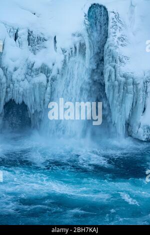 Primo piano del fiume islandese ghiacciato Skjalfandafljot che scorre sulla cascata Godafoss in inverno. Ancora scorre forte ma neve coperta e sott'anguito Foto Stock